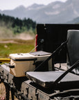 Back of a pickup truck with a cooler and chair in a mountainous landscape