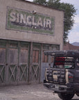 Vintage Sinclair gas station sign on a building with a classic car in the background.