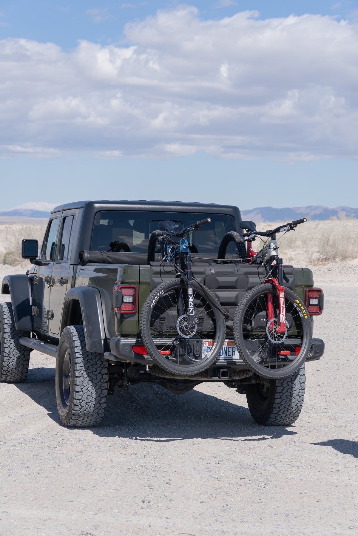 Jeep with bicycles on tailgate pad to the back on a desert landscape