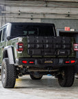 Green pickup truck with a black cargo carrier in front of a building