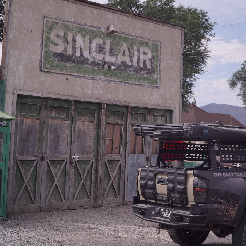 Vintage Sinclair gas station sign on a building with a classic car in the background.