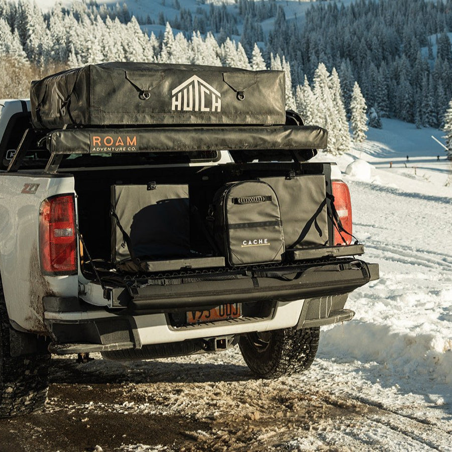 Back of a white truck with Cache outdoor gear in a snowy landscape