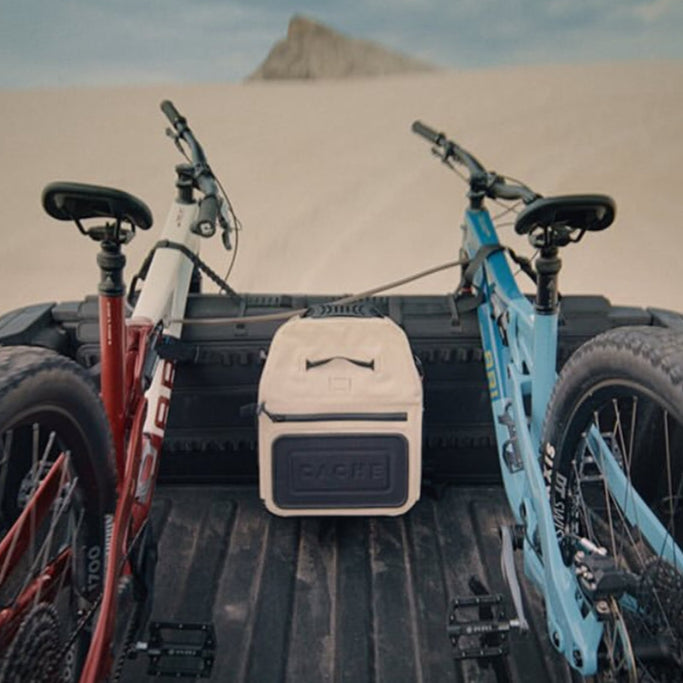 Two bicycles in a truck bed with a desert landscape in the background