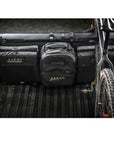 Cache Basecamp System with MOLLE webbing in a truck bed, featuring gear bags and a mounted bicycle