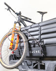 Mountain bike strapped to a truck using a locking padded Cache tailgate cover.