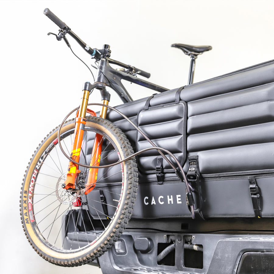 Mountain bike strapped to a truck using a locking padded Cache tailgate cover.