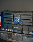 Tailgate of a blue truck with a black Cache pad for securing bikes