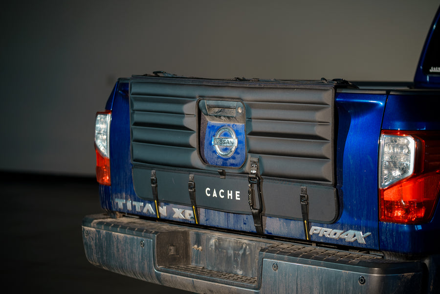 Tailgate of a blue truck with a black Cache pad for securing bikes