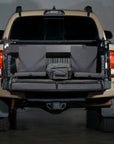 Rear view of a Toyota Tacoma pickup truck with its tailgate down, showcasing a built-in seating setup and cooler