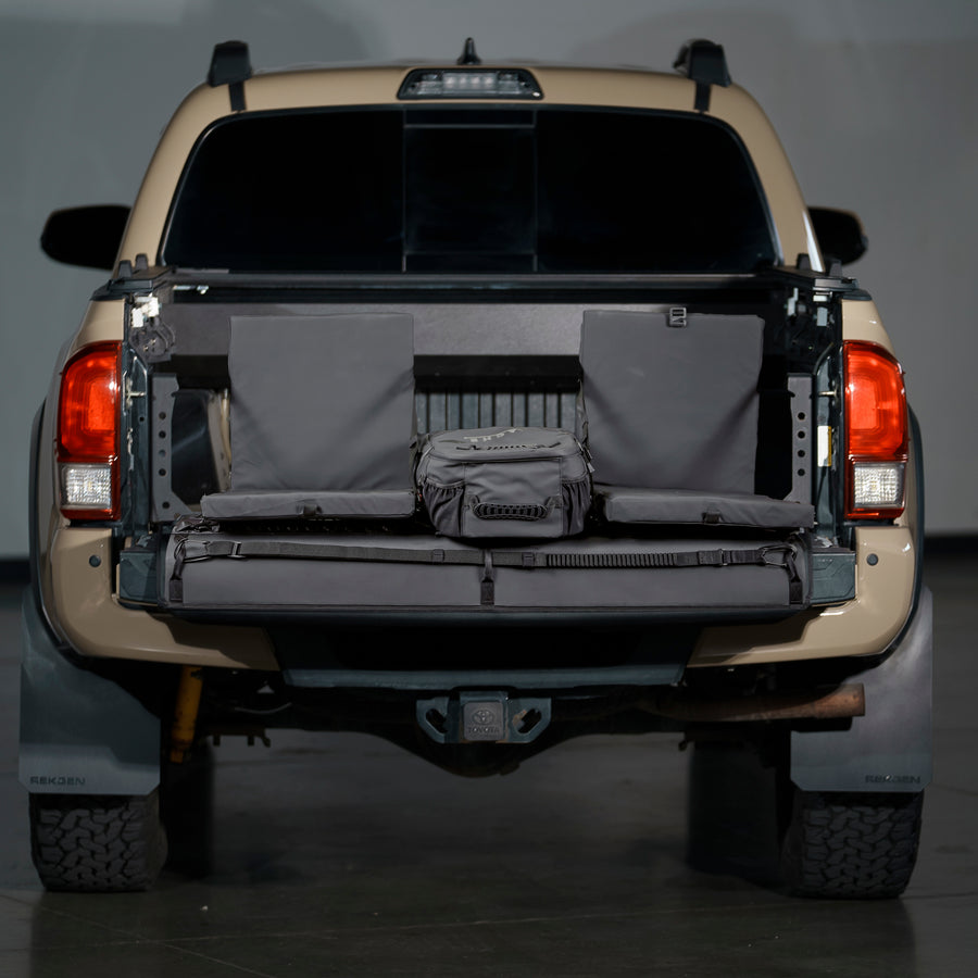 Rear view of a Toyota Tacoma pickup truck with its tailgate down, showcasing a built-in seating setup and cooler