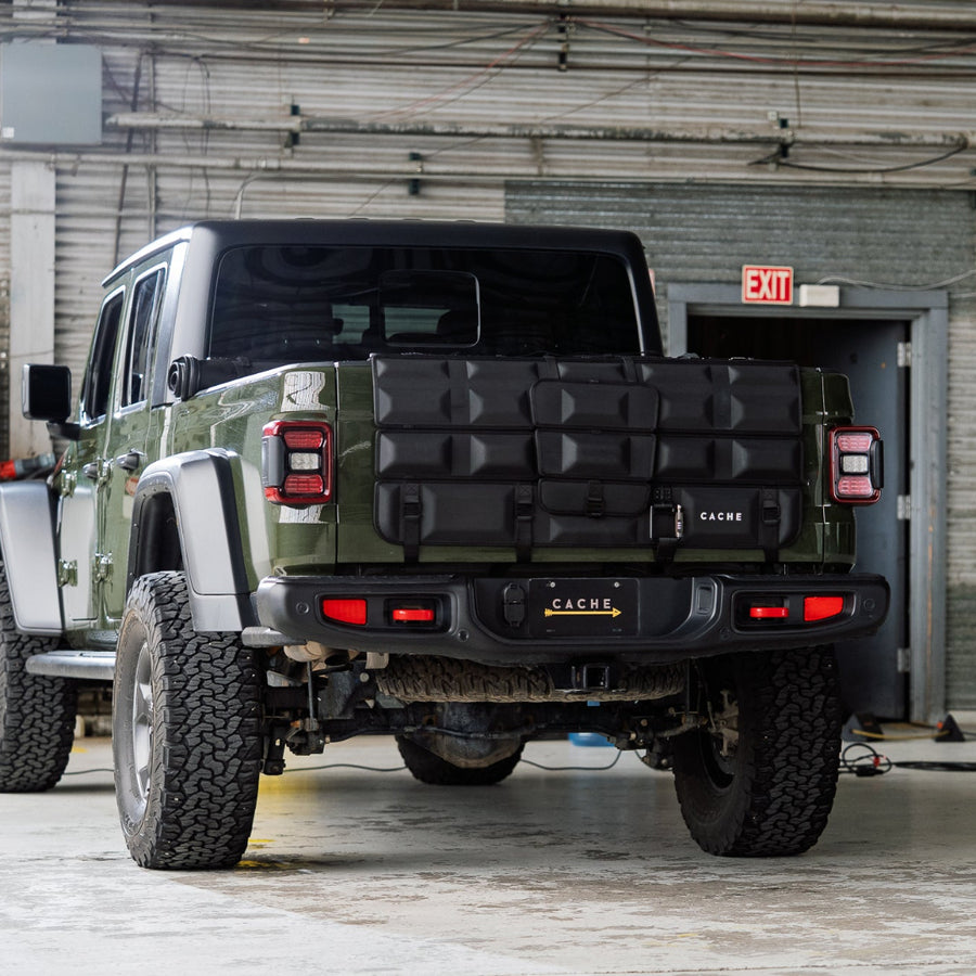 Green pickup truck with a black cargo carrier in front of a building