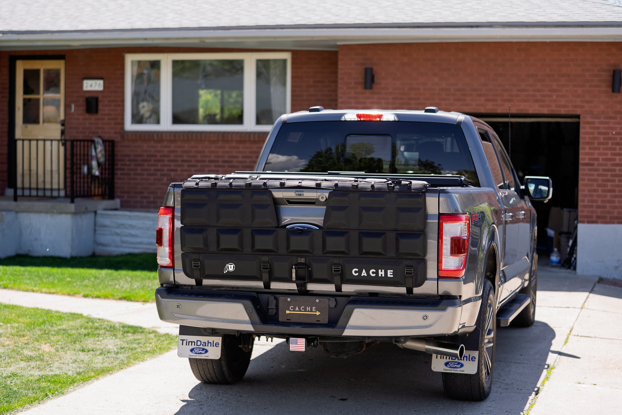 Black pickup truck with 'CACHE' branding parked in front of a house.