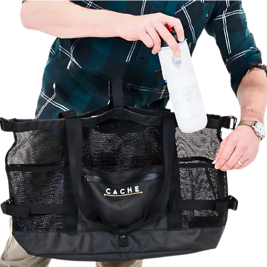 Person holding a black bag with 'CACHE' branding, wearing a plaid shirt.